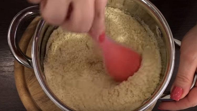 Aggiungi la farina di mandorle allo sciroppo caldo e mescola rapidamente.