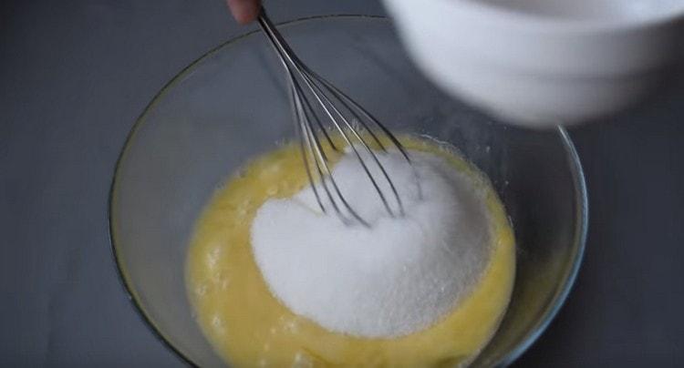 Į kiaušinių masę įpilkite cukraus.