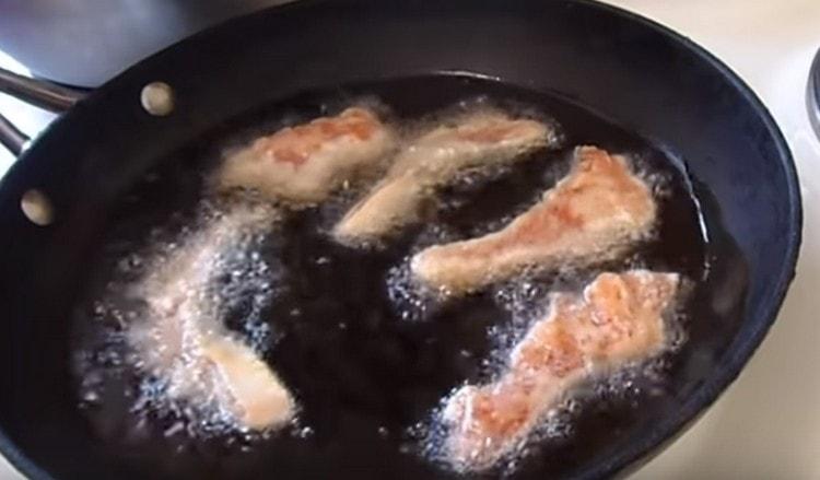 Postupně rozprostřete kousky rybího těsta do zahřátého oleje.