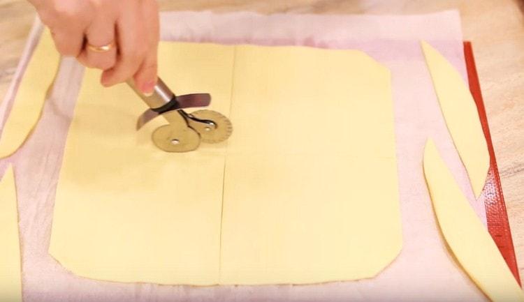 Τυλίξτε το ζαχαροπλαστείο με λεπτό τρόπο. κόψτε το προκύπτον στρώμα σε τετράγωνα.