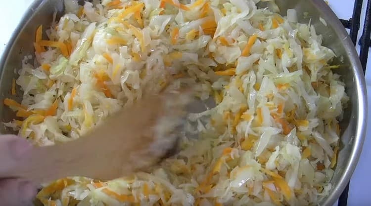 Kohl mit Karotten wird in die Pfanne zur Zwiebel gegeben.