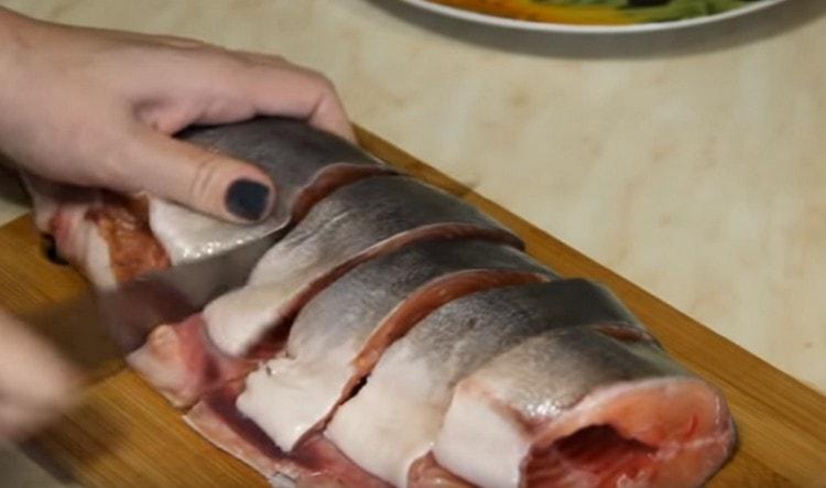 قطع ذبيحة سمك السلمون الوردي إلى أجزاء.