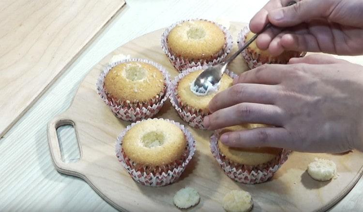 Schneiden Sie die Kerben in den Cupcakes mit einem Messer vorsichtig durch und füllen Sie sie mit Sahne.