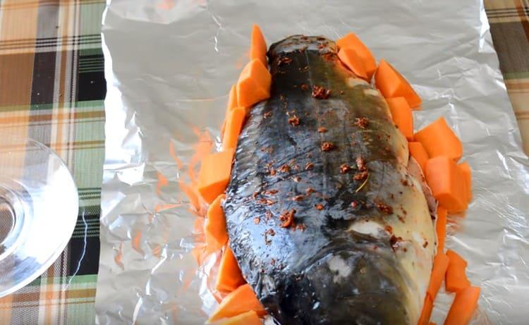 Покриваме рибата с морковни пръчици.