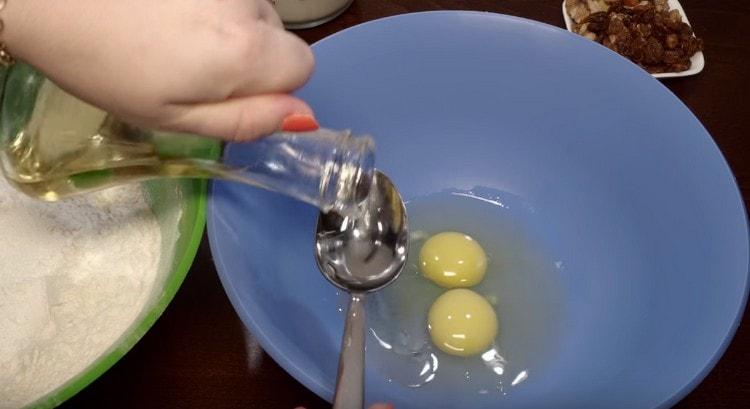 Zwei Eier in eine Schüssel geben, Pflanzenöl hinzufügen.