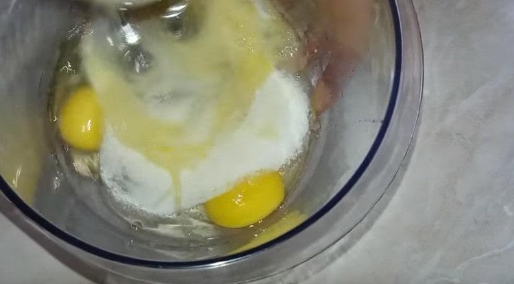 Fügen Sie Zucker zu den Eiern hinzu und schlagen Sie die Masse mit einem Mixer.