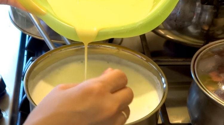 إدخال كتلة البيض في الحليب المغلي في تيار رقيقة.