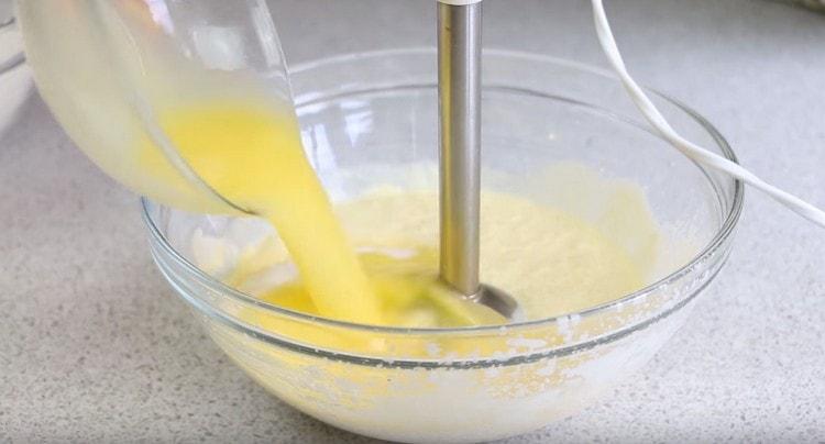 Προσθέστε αυγά στο τυρόπηγμα, καθώς και λιωμένο βούτυρο.