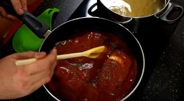 Fügen Sie Tomatenmark und Kräuter der Provence zu den Hähnchenbrust in der Pfanne hinzu.