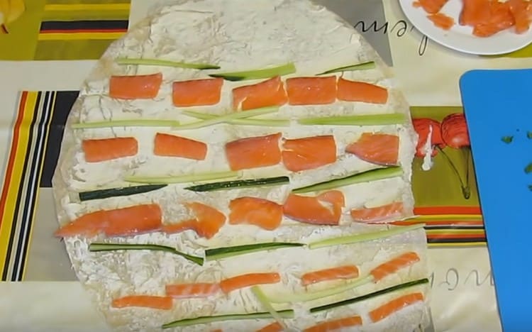 Auf gefettetem Fladenbrot legen wir Fisch- und Gurkenstücke aus.
