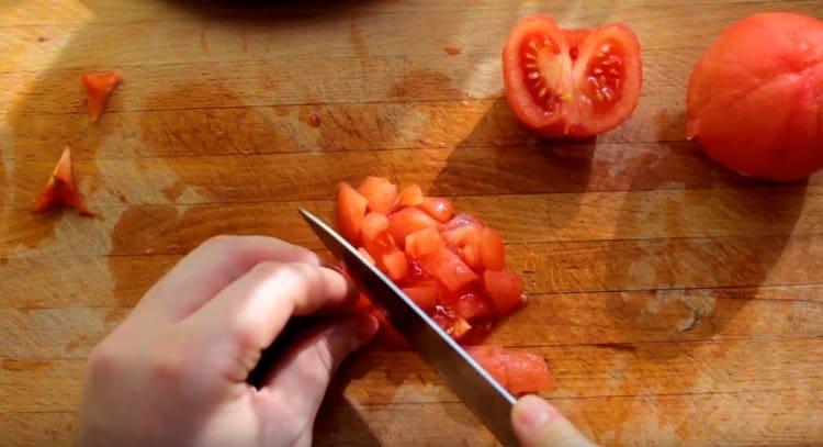 Нарежете обелените домати.