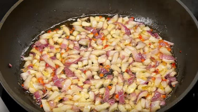 Σε μια κατσαρόλα με ελαιόλαδο, τηγανίζουμε τα κρεμμύδια και τις πιπεριές τσίλι.