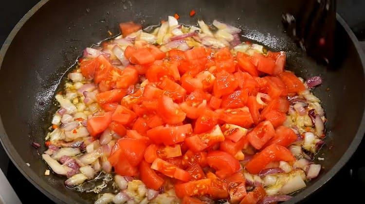 Į keptuvę įpilkite pomidorų.