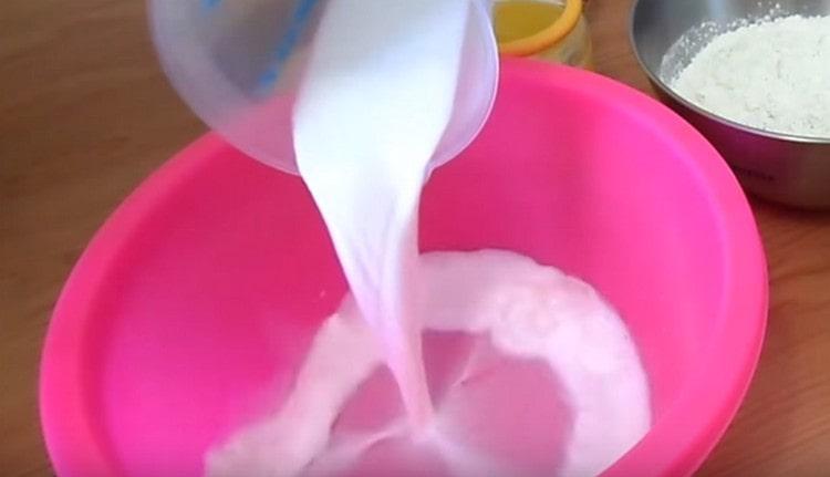 Gießen Sie warme Milch in eine Schüssel, um den Teig zu kneten.