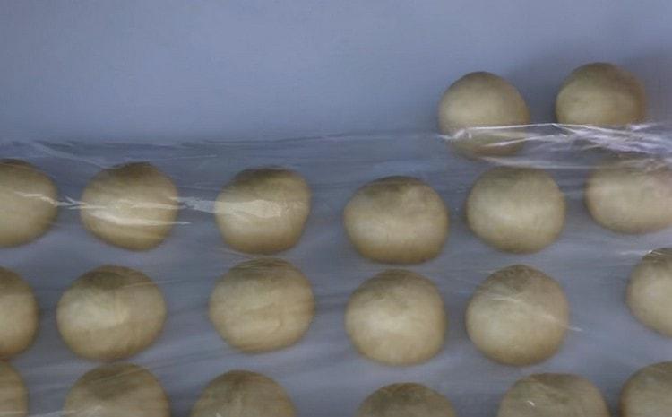 След като разточваме топки от парчета тесто, ги покриваме с прилепнал филм.