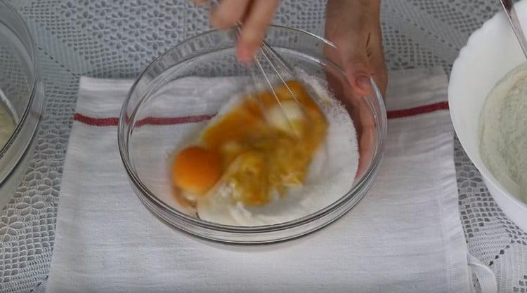 Με ένα χτυπητήρι, ανακατέψτε τα αυγά με ζάχαρη.