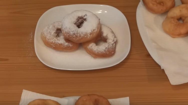 In einer Pfanne gekochte Donuts können mit Puderzucker bestreut werden.