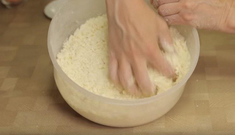 Fügen Sie den Hüttenkäse in Mehl mit Butter hinzu und mahlen Sie alles in Krümel.