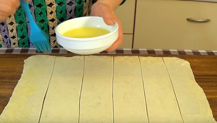 Namažte každý proužek těsta rozpuštěným máslem.