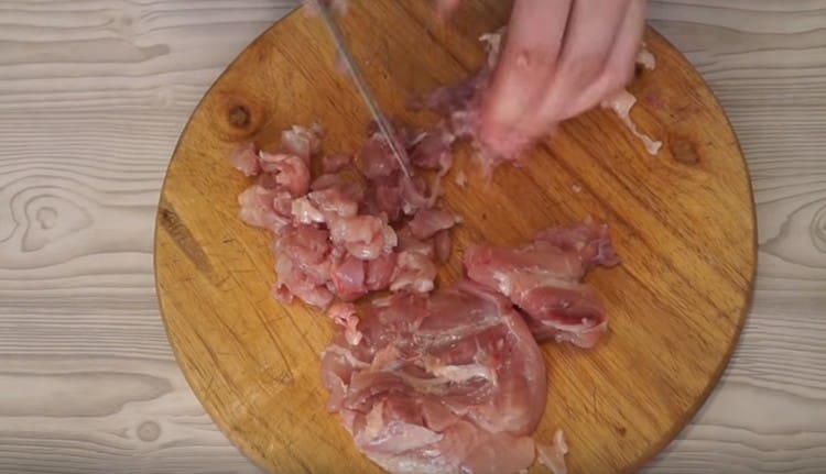 Нарежете месото с мазнина от пилешките бедра.