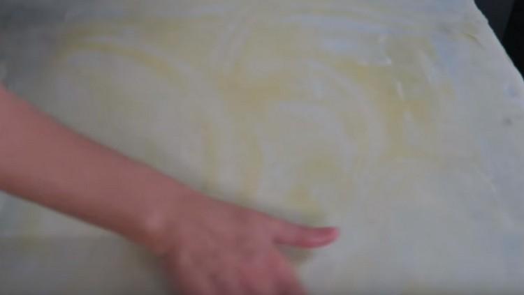 Lubrificare lo strato di pasta risultante con burro fuso in acqua calda.