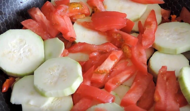 Į keptuvę įpilkite cukinijos su pomidorais.