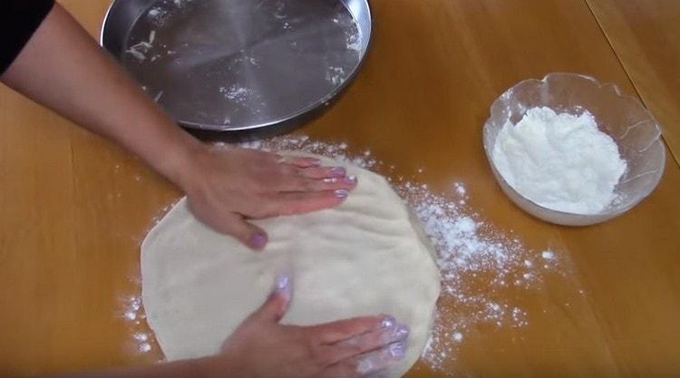 Gautas pyragas sutankinamas rankomis ant darbinio paviršiaus.