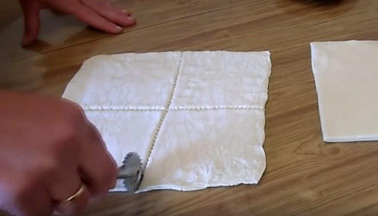 Den Teig etwas ausrollen und in Quadrate schneiden.