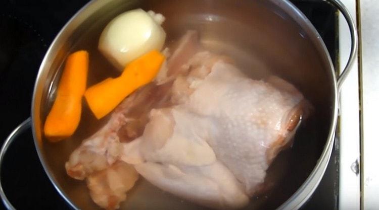 Разпределяме пилешкото месо, лука и моркова в тиган, наливаме вода.