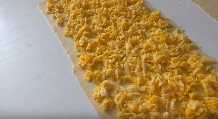 Πάνω από ένα κομμάτι ζύμης διανέμεται το τυρί.