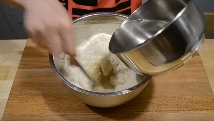 Introduciamo acqua bollente nella farina e mescoliamo rapidamente.