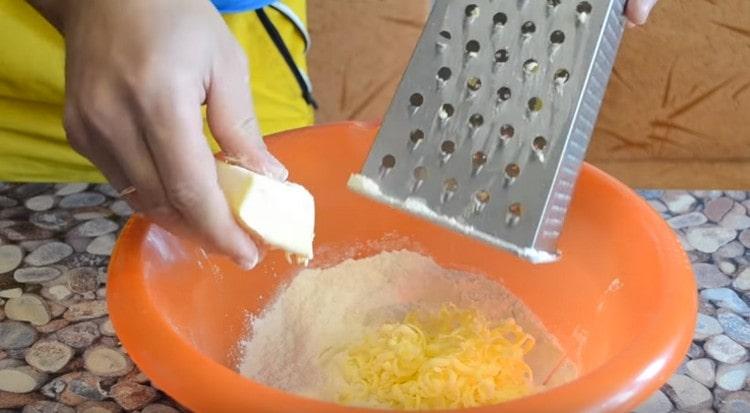 Auf einer Reibe reiben wir gefrorene Butter in Mehl.