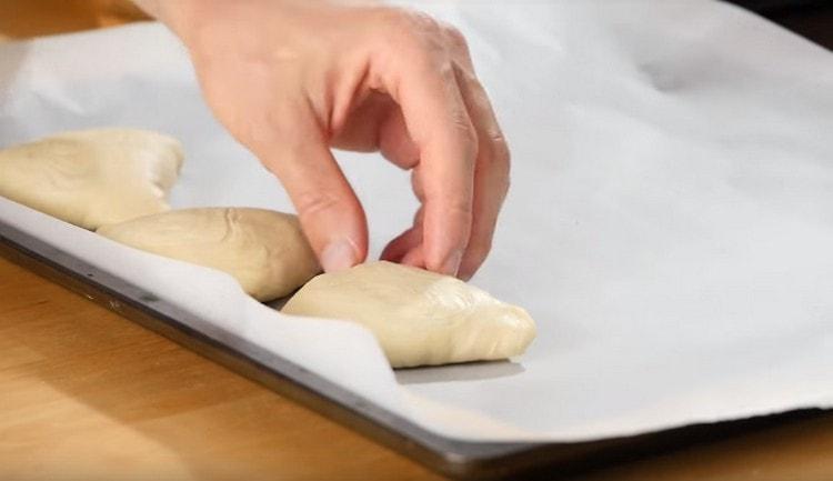 على ورقة الخبز المغطاة برق ، ضع السمسا مع التماس لأسفل.