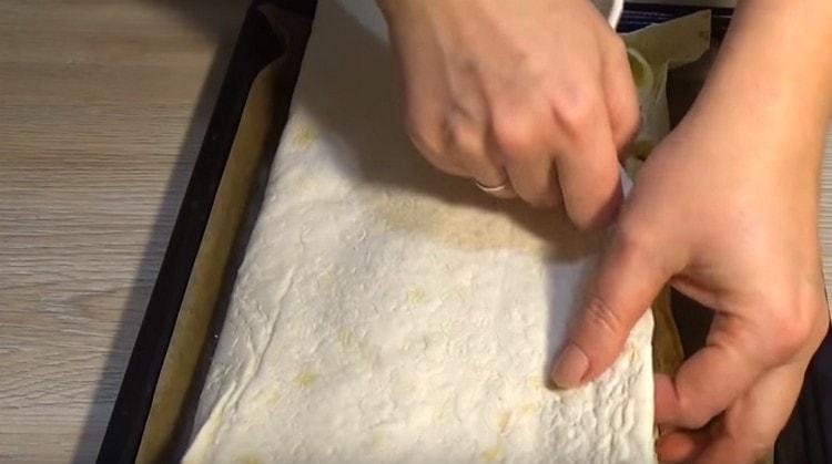 Покрийте пълнежа с навлажнени парчета от пита питка и след това покрийте цялата структура със свободния ръб на питата.