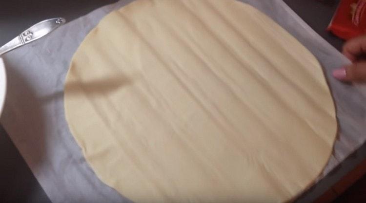 Sa baking sheet ipinakalat namin ang pergamino, inilagay ang pinagsama na puff pastry dito.
