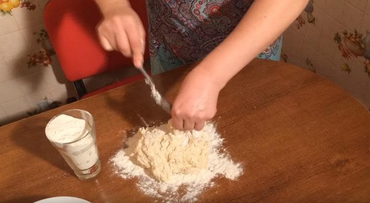 Изсипете останалото брашно на масата и прехвърлете тестото в него.