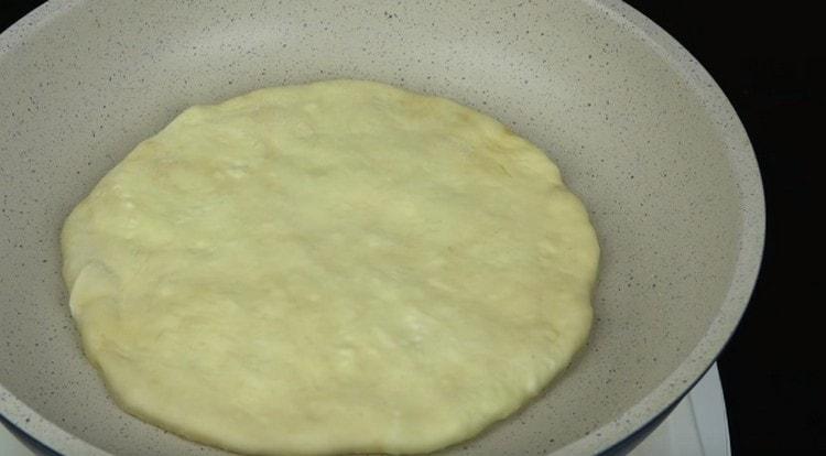 Friggere i Khachapuri con il formaggio in una padella asciutta.