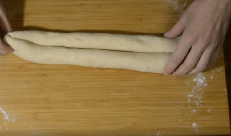 Разделяйки тестото наполовина, всяко парче се разточва на тънко, след това се усуква към центъра от единия и от другия ръб с руло.