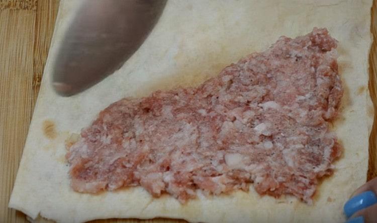A pita kenyér egyik felén háromszöggel eloszlatjuk a darált húst.