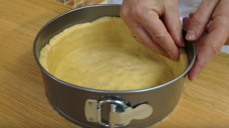 szétterítjük a tésztát egy formába, és vízszintesen alakítjuk ki, az alapot képezve az oldalakkal.