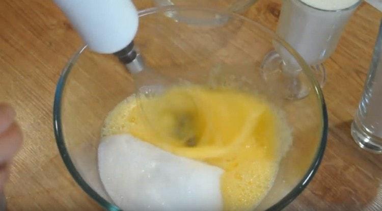 Į kiaušinius įpilkite stiklinę cukraus.