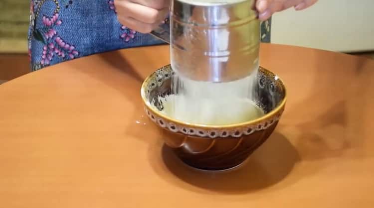 Sieben Sie Mehl, um Brötchen mit Marmelade zu machen