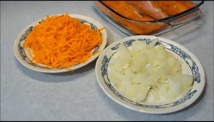 Taglia cipolle e carote per preparare il salmone rosa