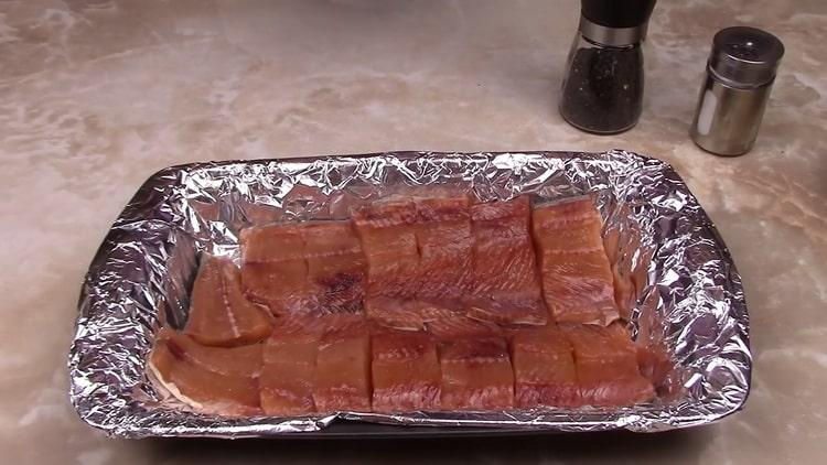 Um rosa Lachs in einer cremigen Sauce zuzubereiten, legen Sie den Fisch in ein Backblech