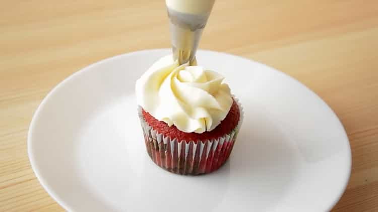 Per preparare cupcake di velluto rosso, lascia cadere la crema sul cupcake