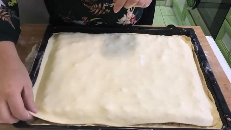 Um Baklava aus Blätterteig zu machen, bedecken Sie die oberste Schicht mit Teig