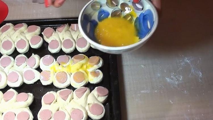 Bevert tojást, hogy kolbászpiteket készítsen.