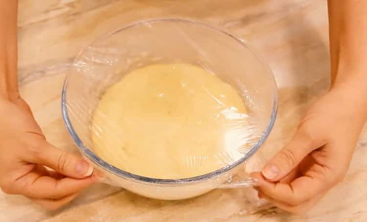 Um Krapfen im Ofen zuzubereiten, legen Sie den Teig unter eine Folie