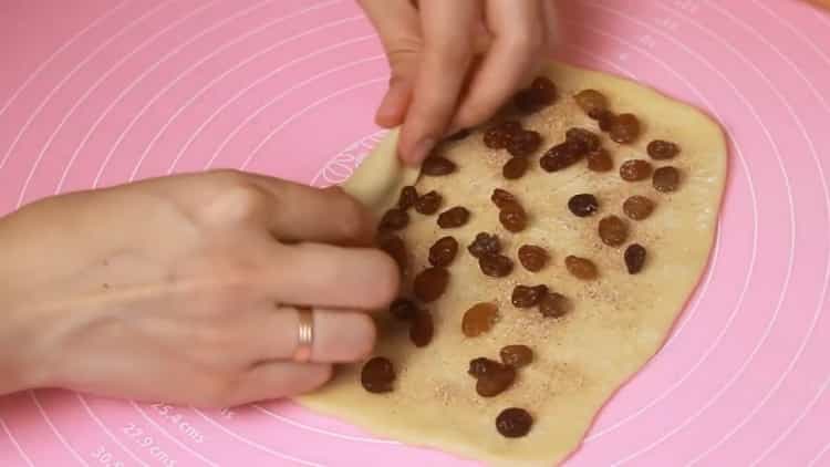 За да направите кифлички, поставете стафиди върху тестото