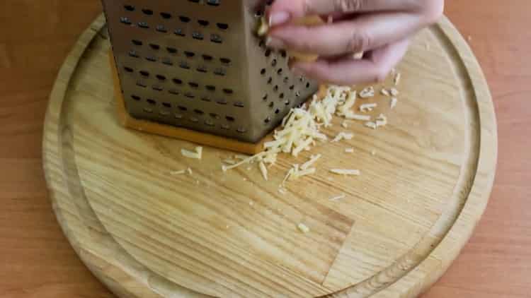 A sült makréla zöldségekkel történő főzéséhez reszelje le a sajtot